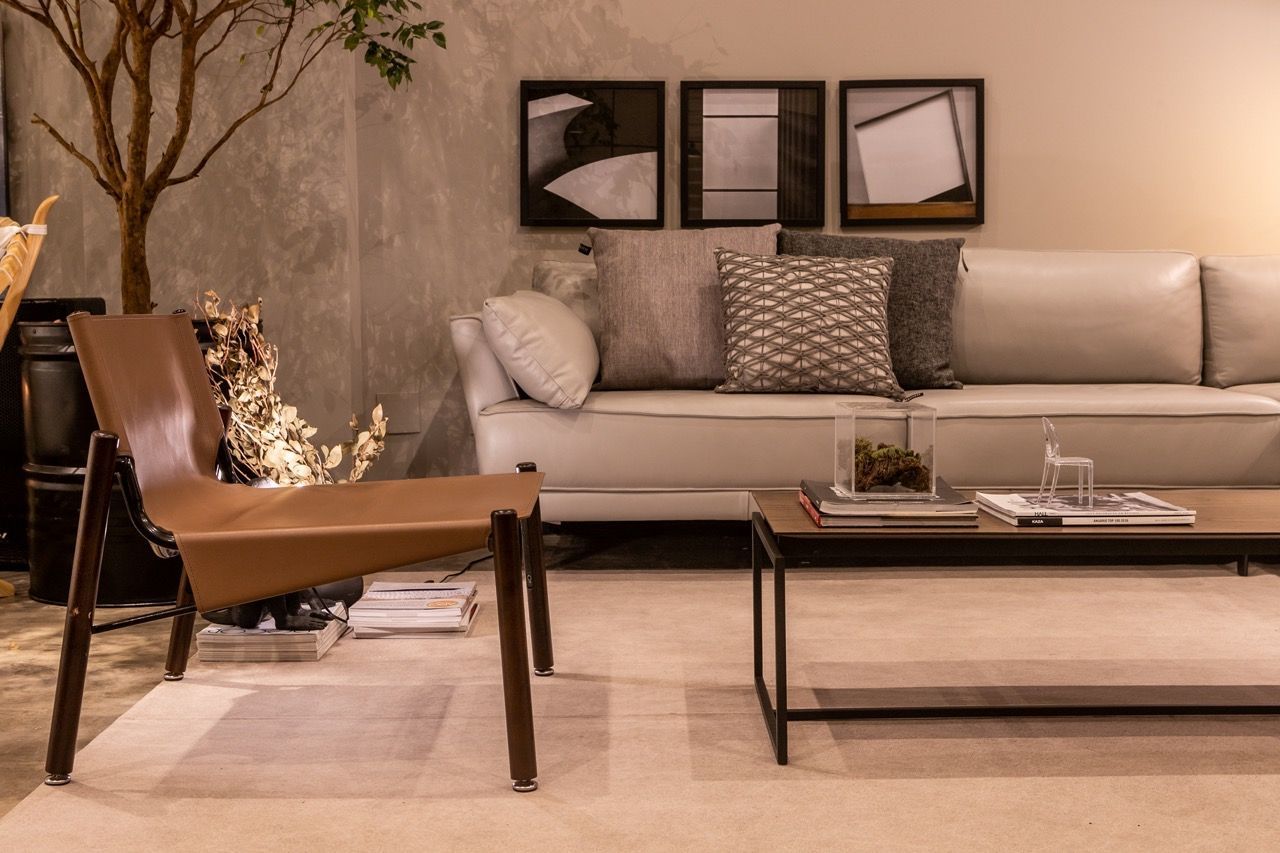 Uma sala com sofá, cadeira, mesa de centro e quadros na parede.