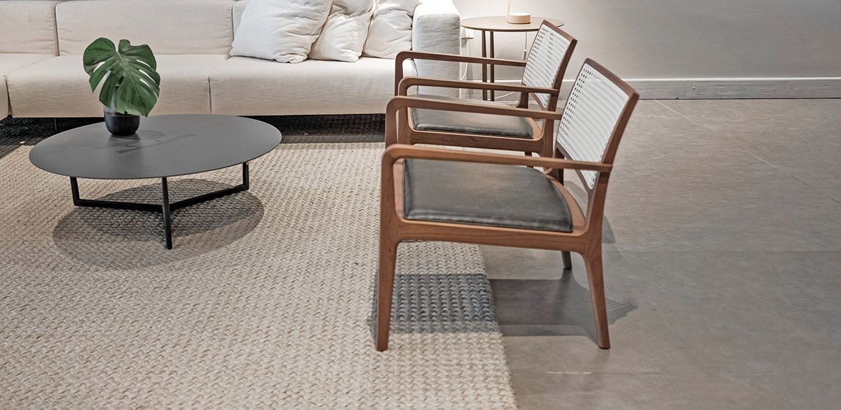 Uma sala de estar com sofá, cadeiras, mesa de centro e tapete.