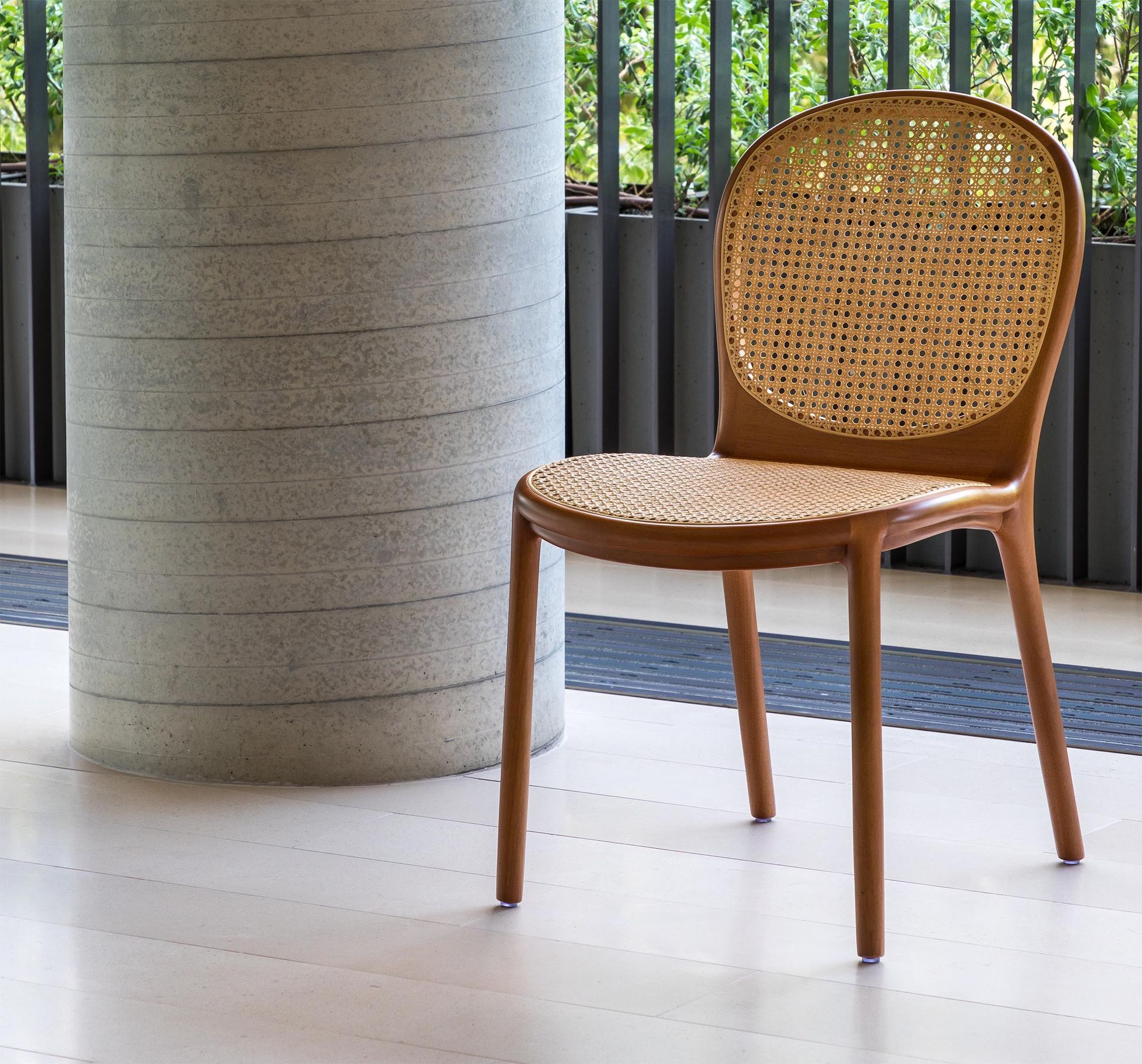 Uma cadeira com encosto de vime fica em frente a um pilar