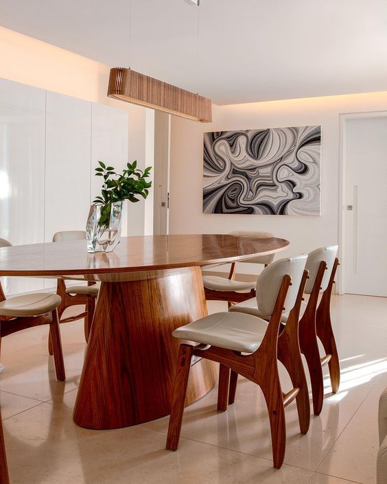 Uma sala de jantar com mesa e cadeiras e um quadro na parede.