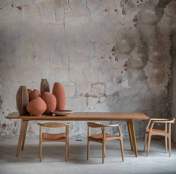 Uma mesa com cadeiras e vasos em frente a uma parede