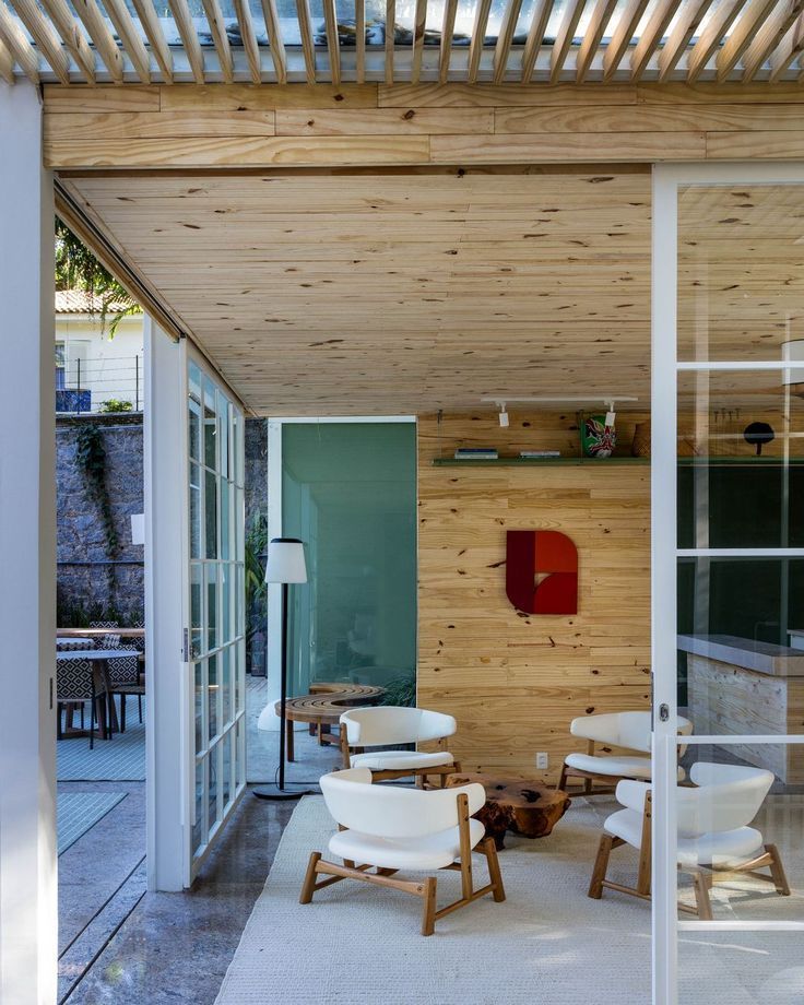 Uma sala de estar com teto de madeira e cadeiras brancas