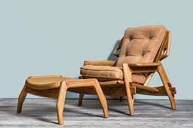 Uma cadeira e um pufe estão sentados sobre um chão de madeira.