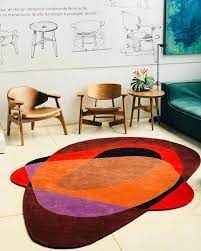 Sala de estar com tapete, cadeiras e sofá.