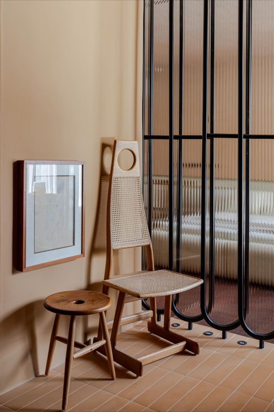 Há uma cadeira e um banquinho no canto da sala.