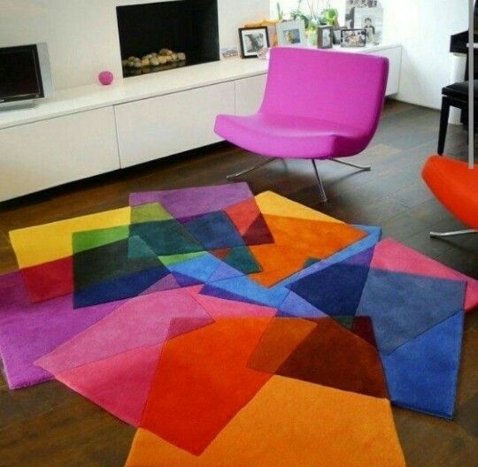 Uma sala com uma cadeira roxa e um tapete colorido