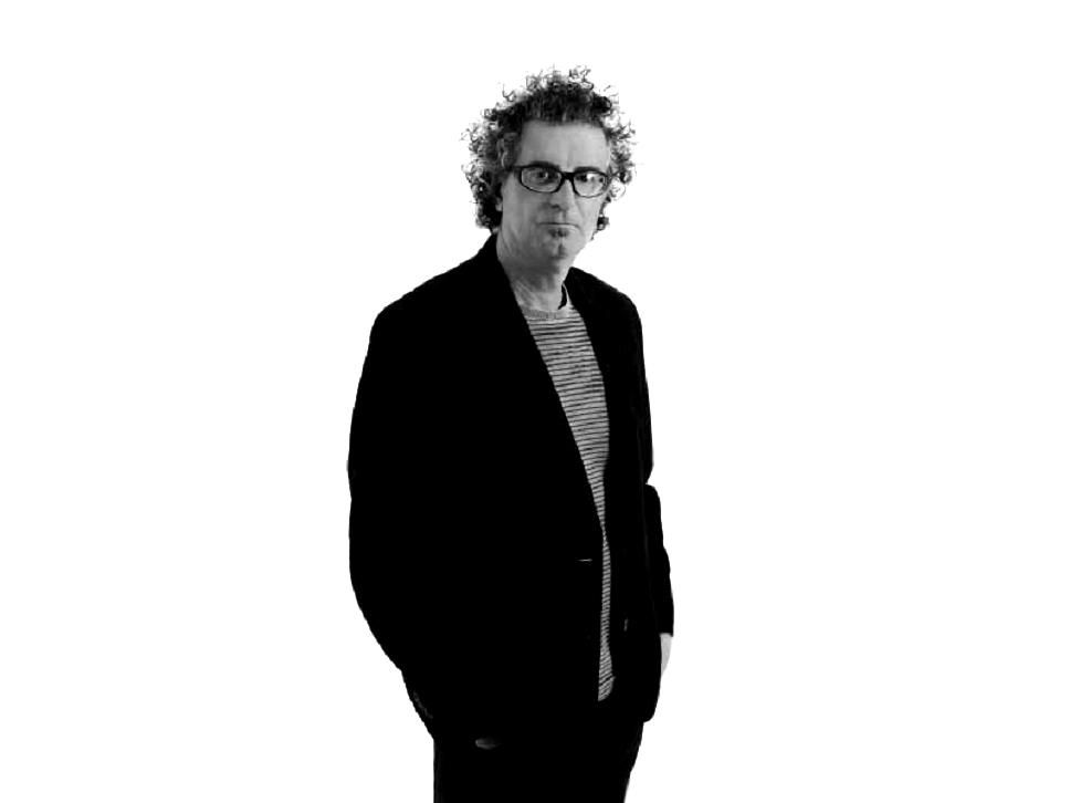 Um homem de terno e óculos está parado em frente a um fundo branco.