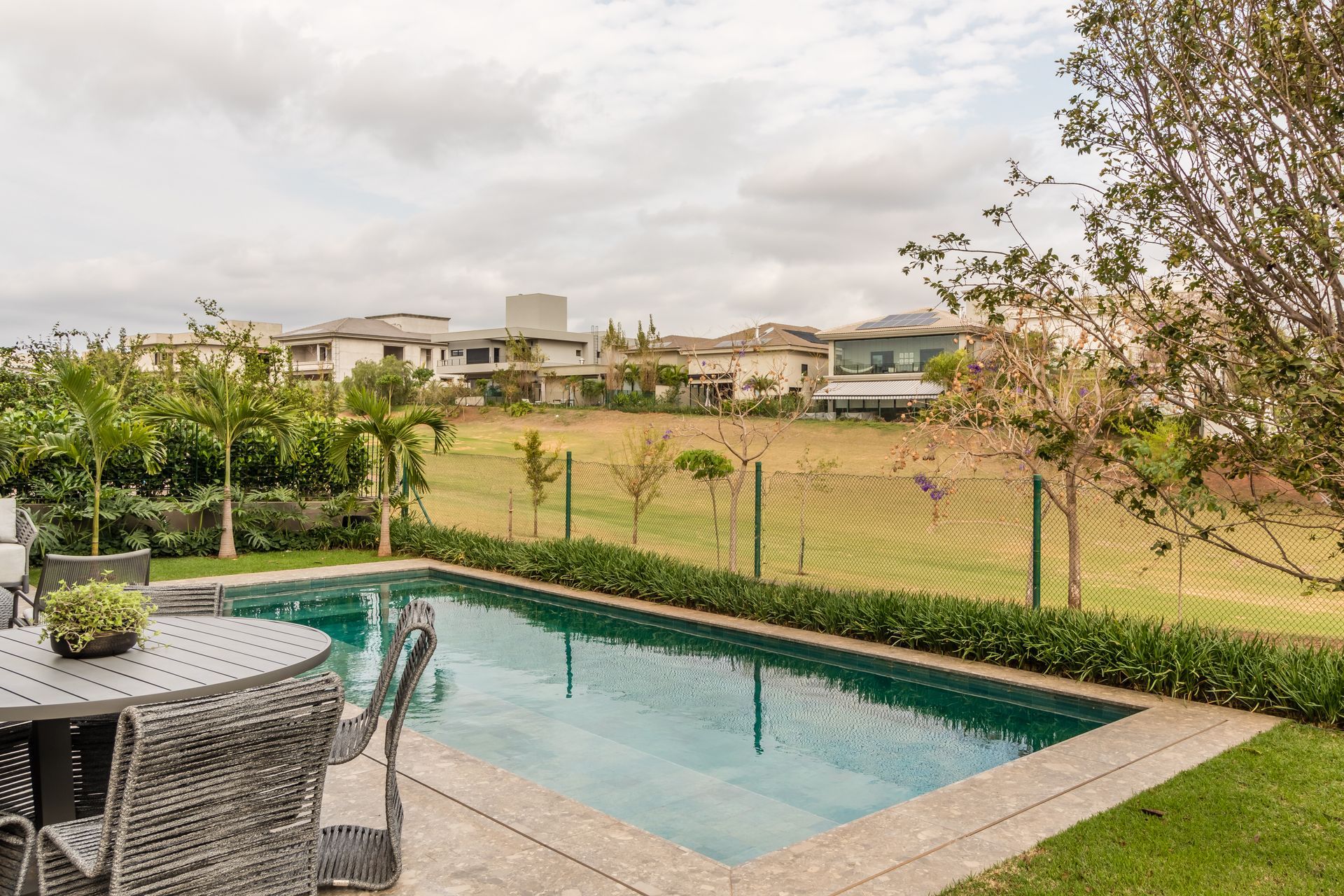 Há uma grande piscina no quintal com mesa e cadeiras.