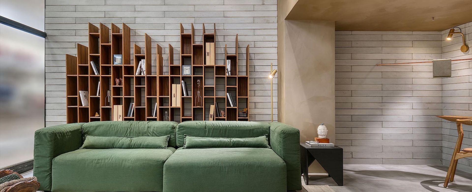 Sala de estar com sofá verde e estante.