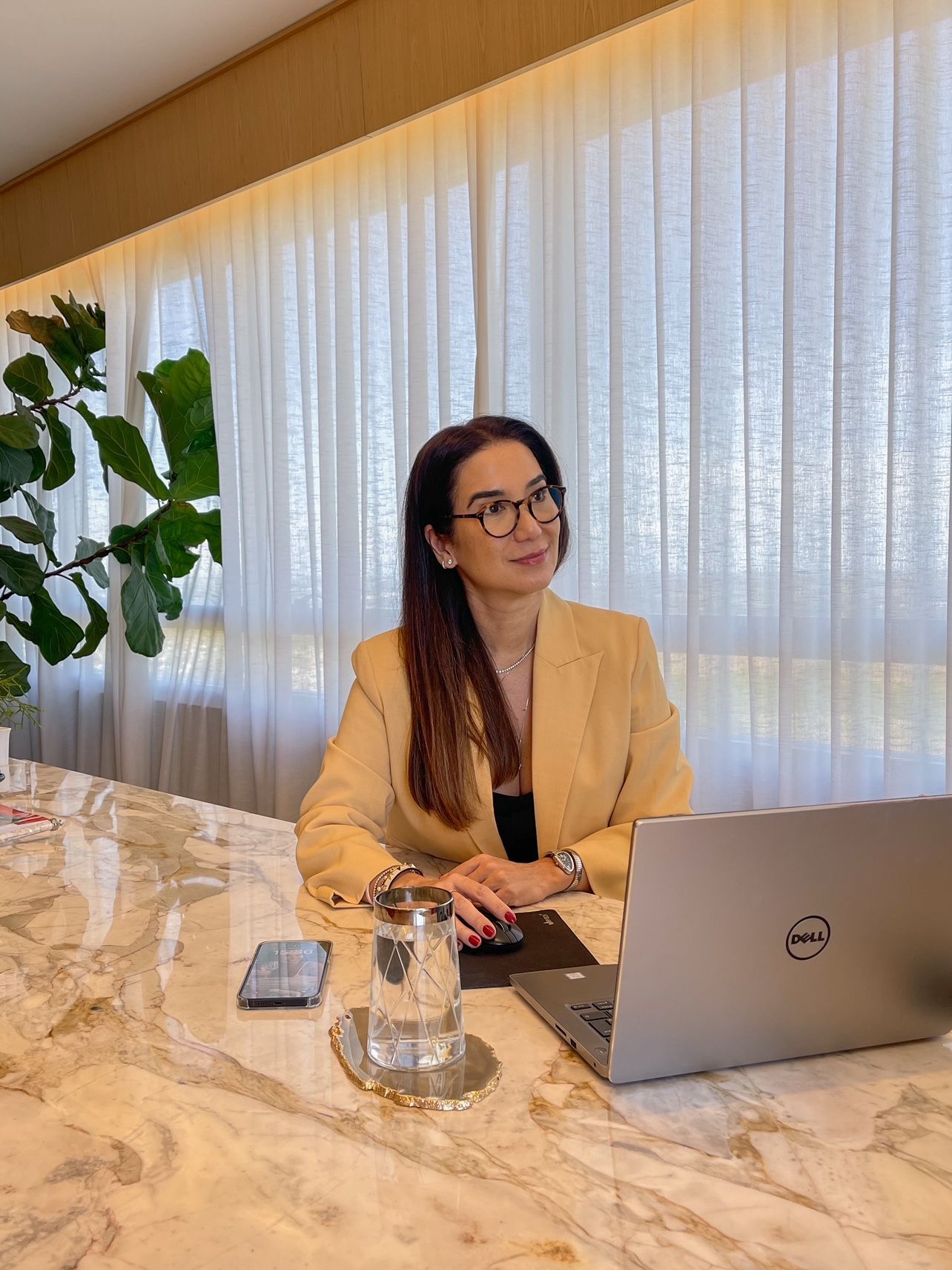 Uma mulher está sentada à mesa com um laptop.