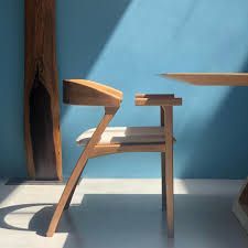 Uma cadeira de madeira está ao lado de uma mesa de madeira em uma sala com parede azul.