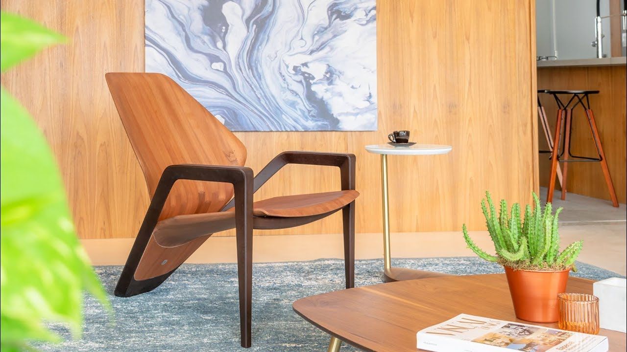 Uma cadeira de madeira está em uma sala de estar ao lado de uma mesa de centro.