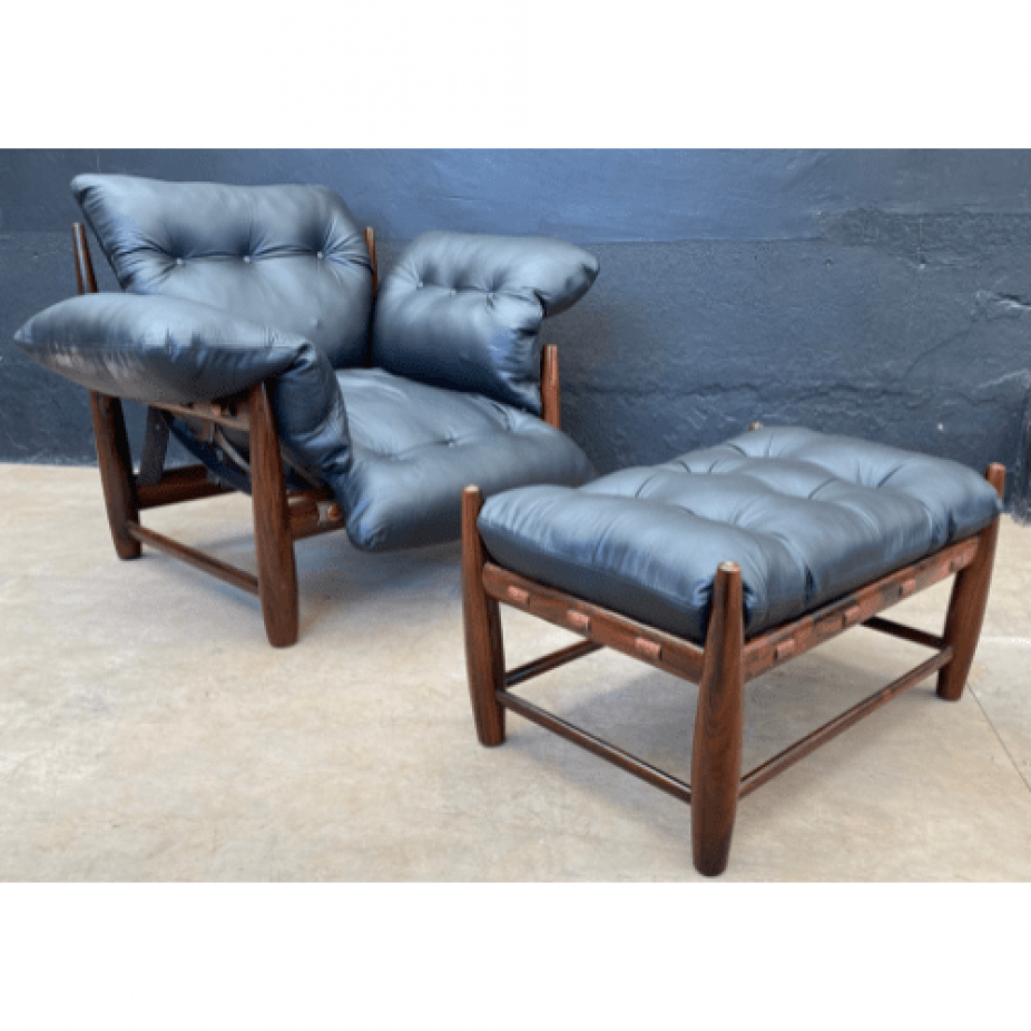 Uma cadeira de couro preto e um pufe estão sentados um ao lado do outro