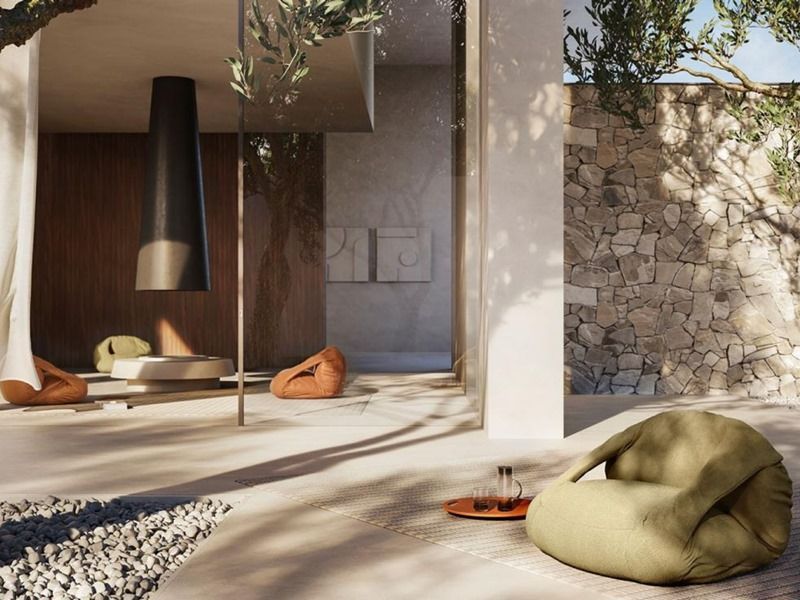 Um pufe verde está sentado em um pátio próximo a uma parede de pedra.