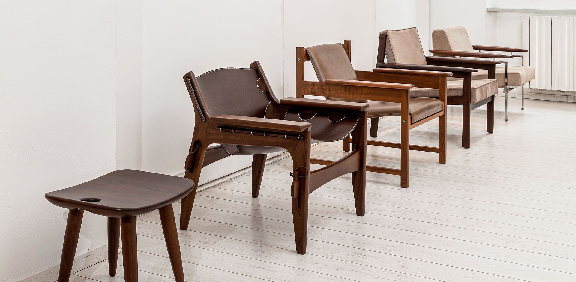 Uma fileira de cadeiras e um banquinho estão alinhados em uma sala.