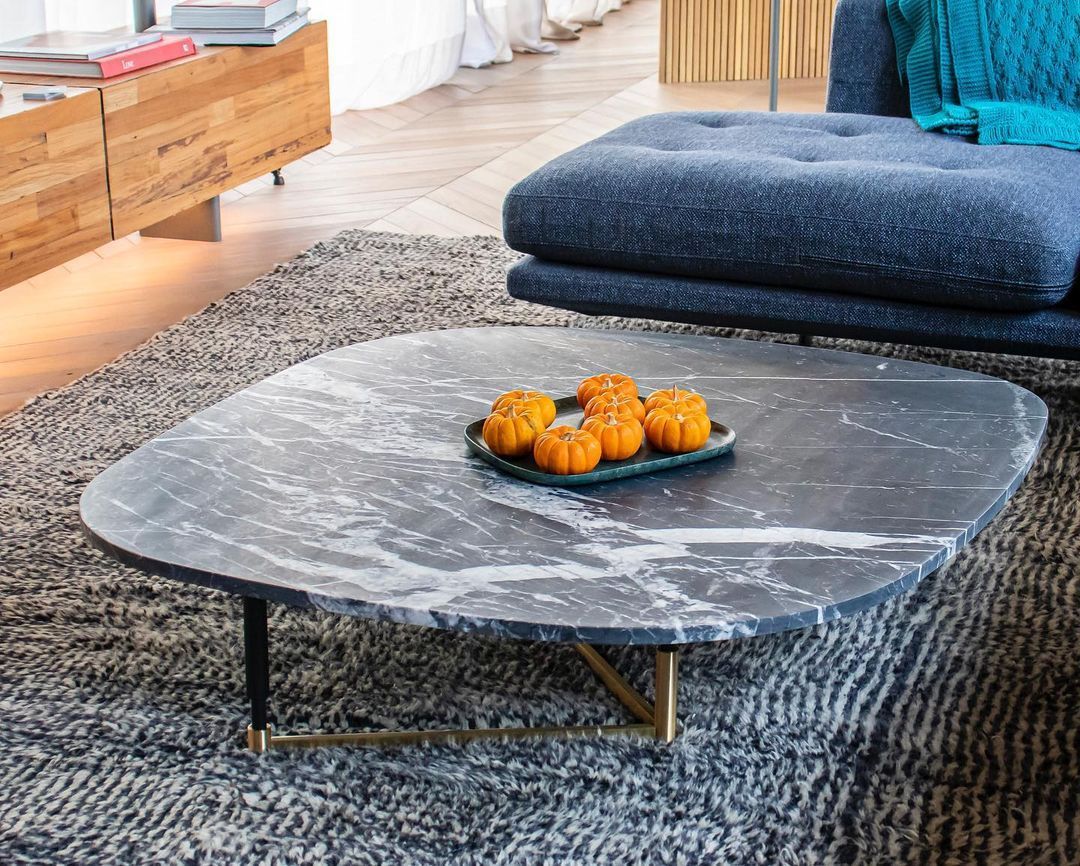 Uma mesa de centro com uma bandeja de laranjas em uma sala de estar.