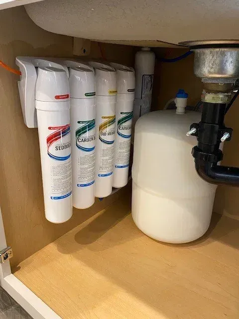 A water filter is installed under a sink in a kitchen.