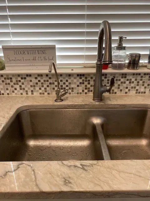 A kitchen sink with a faucet and a sign on the counter.