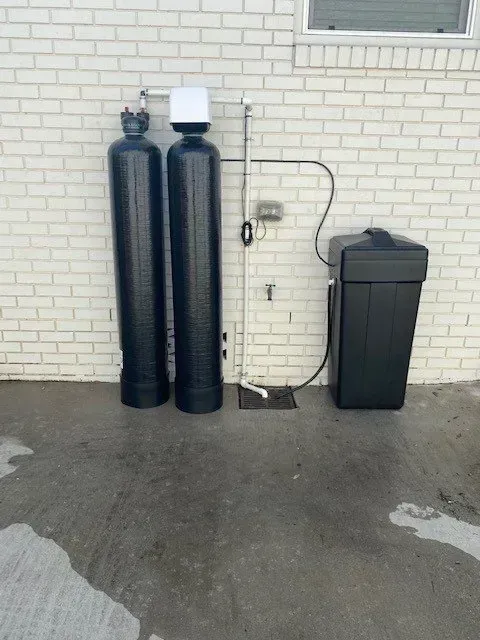 Two black cylinders are sitting next to each other in front of a white brick wall