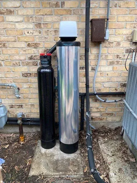 A water filter is sitting outside of a brick building.