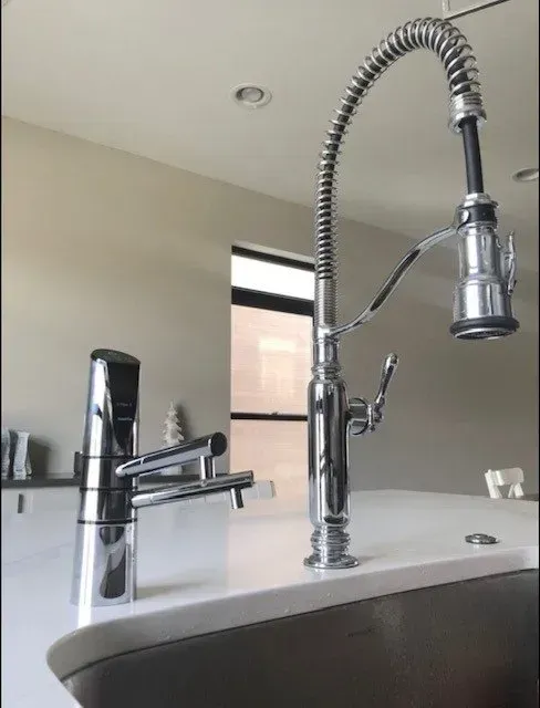 A kitchen sink with a faucet and a window in the background