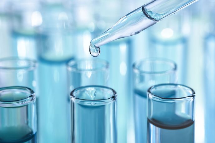 A drop of liquid is being poured into a test tube.