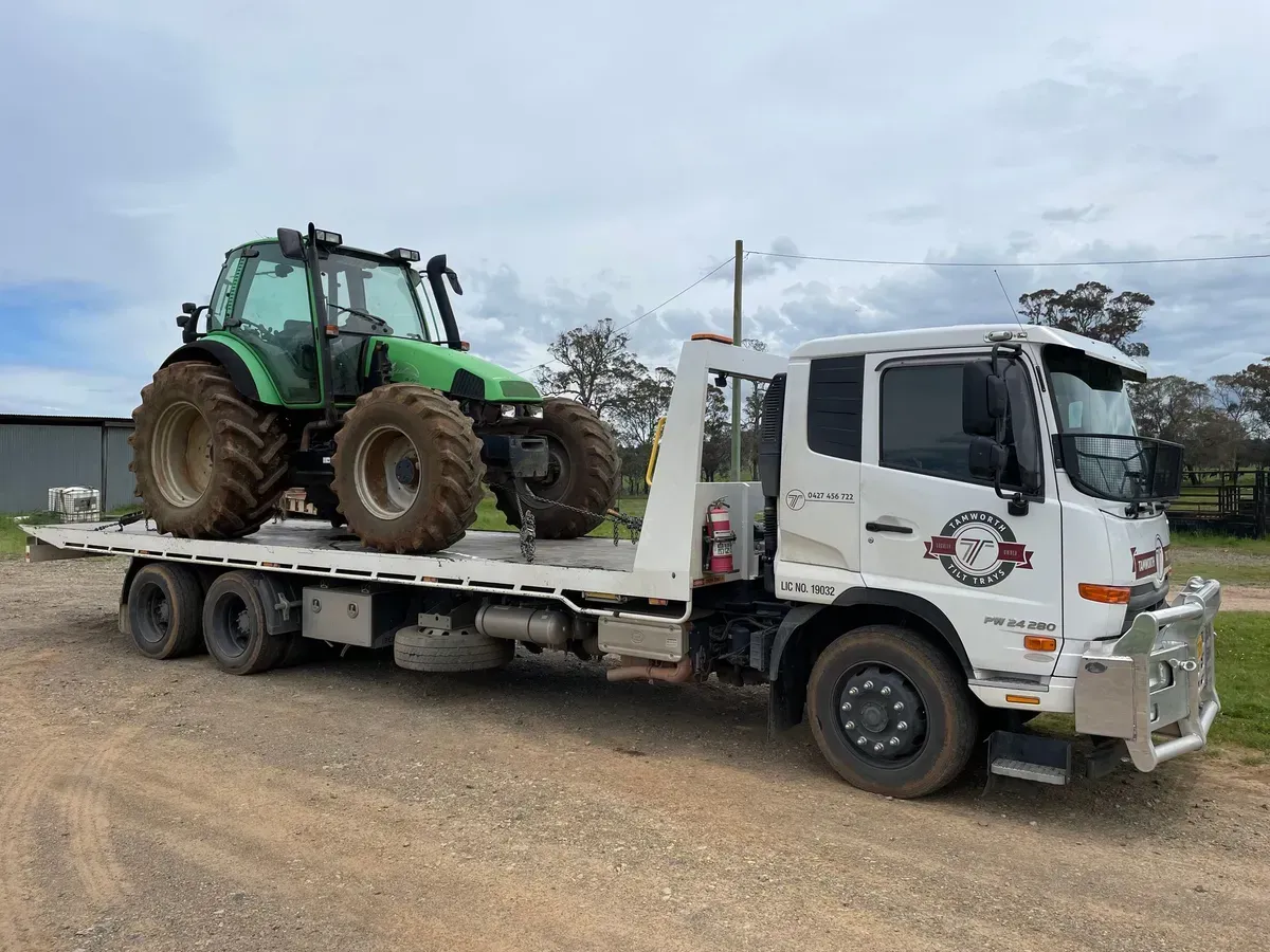 A White Flatbed Tow Truck Carrying a Large Green Farm Tractor — Tamworth Tilt Trays in Tamworth, NSW
