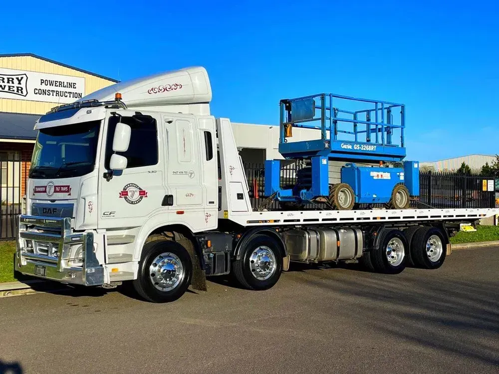 A White Flatbed Truck Parked Outdoors Carrying a Blue Scissor Lift — Tamworth Tilt Trays in Tamworth, NSW