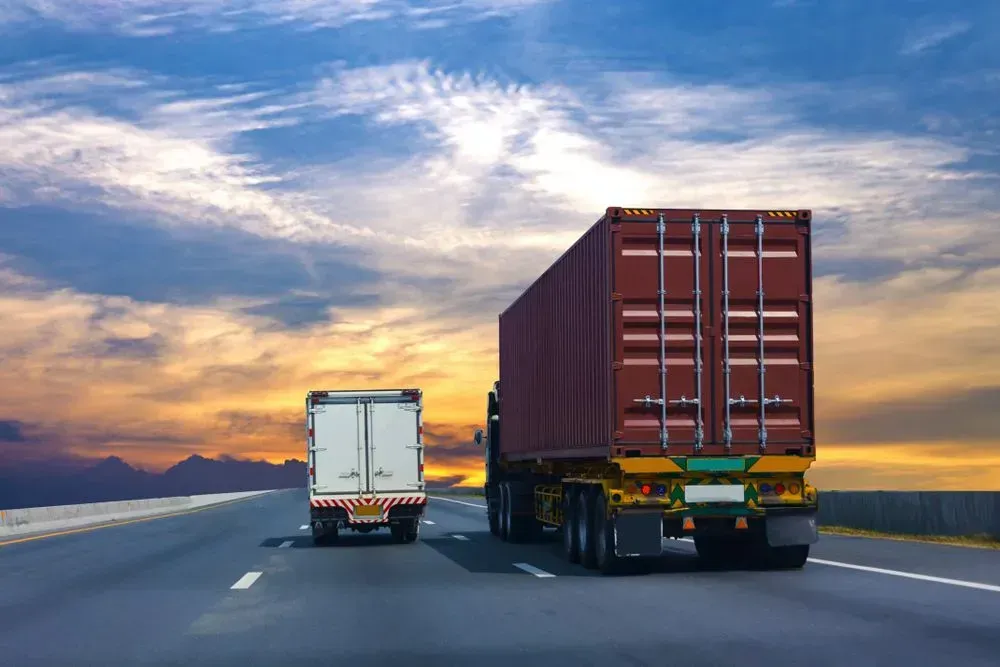A Semi-Truck and a Smaller Box Truck Drive on a Highway — Tamworth Tilt Trays in Tamworth, NSW