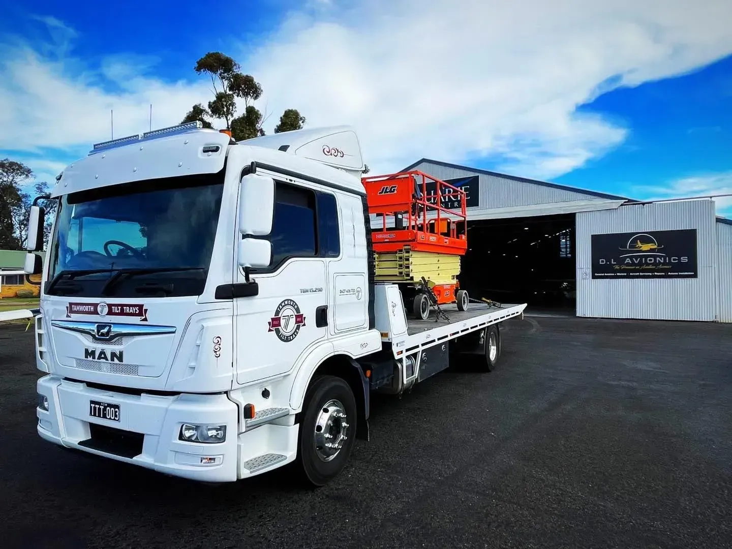 A White MAN Flatbed Tow Truck Carrying an Orange Scissor Lift — Tamworth Tilt Trays in Tamworth, NSW