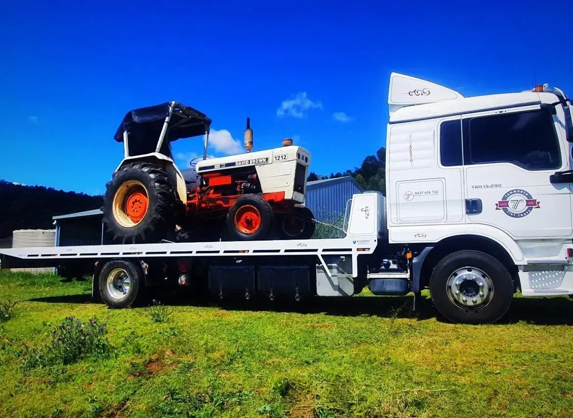 A White Tractor Loaded Onto a Flatbed Tow Truck — Tamworth Tilt Trays in Tamworth, NSW