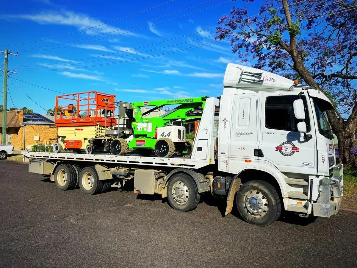 A White Tow Truck Hauling an Orange Scissor Lift and a Green Boom Lift — Tamworth Tilt Trays in Tamworth, NSW