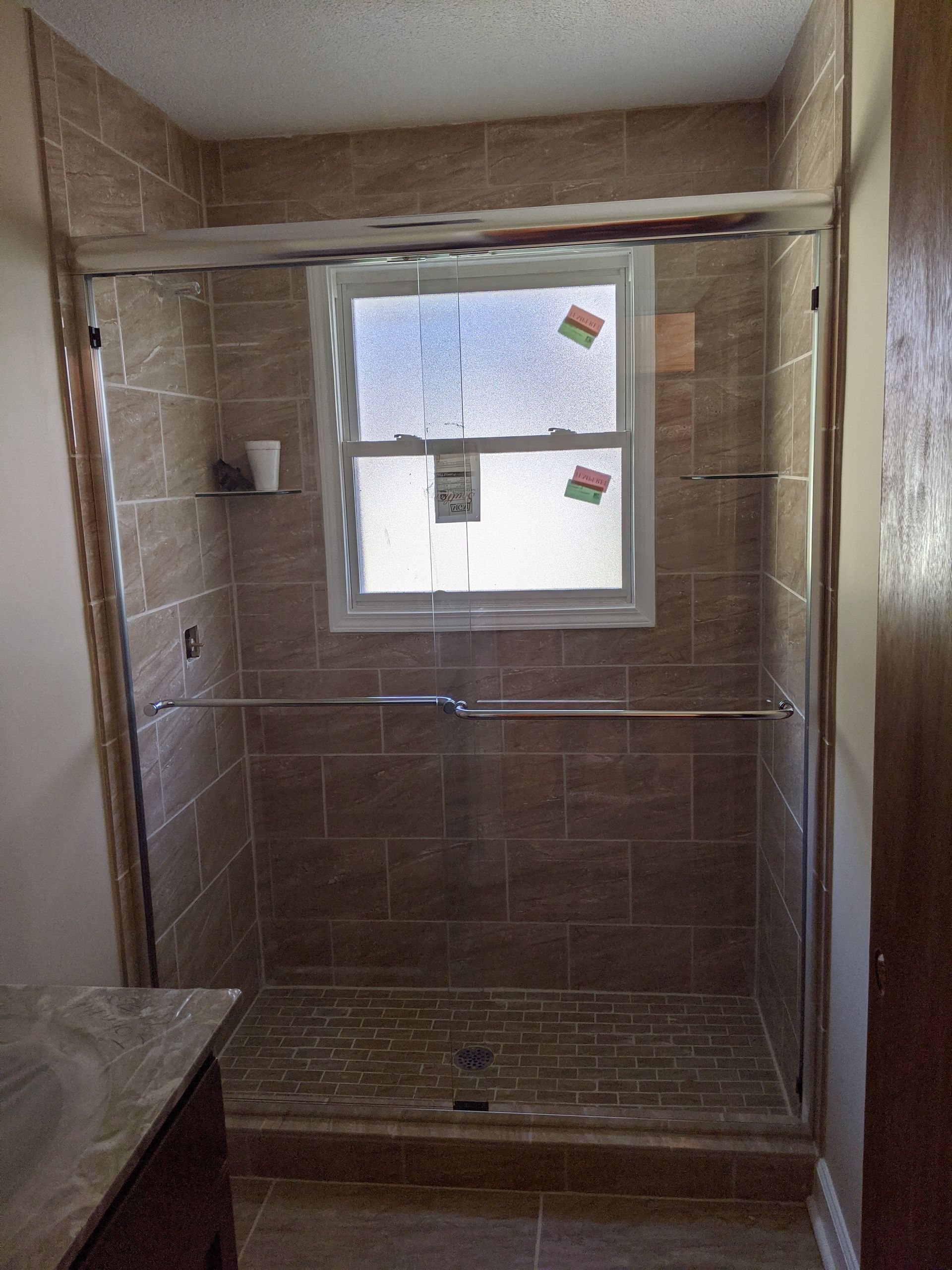 A bathroom with a sliding glass shower door and a window.