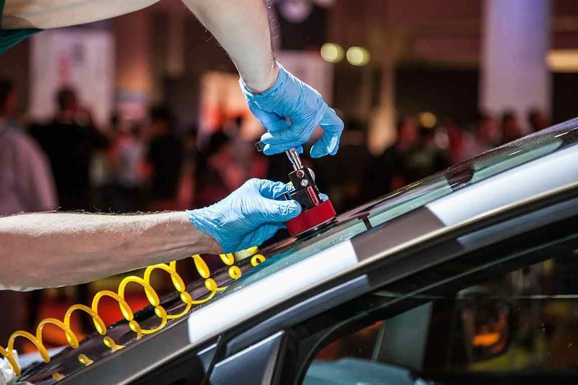 A man is fixing a windshield on a car.