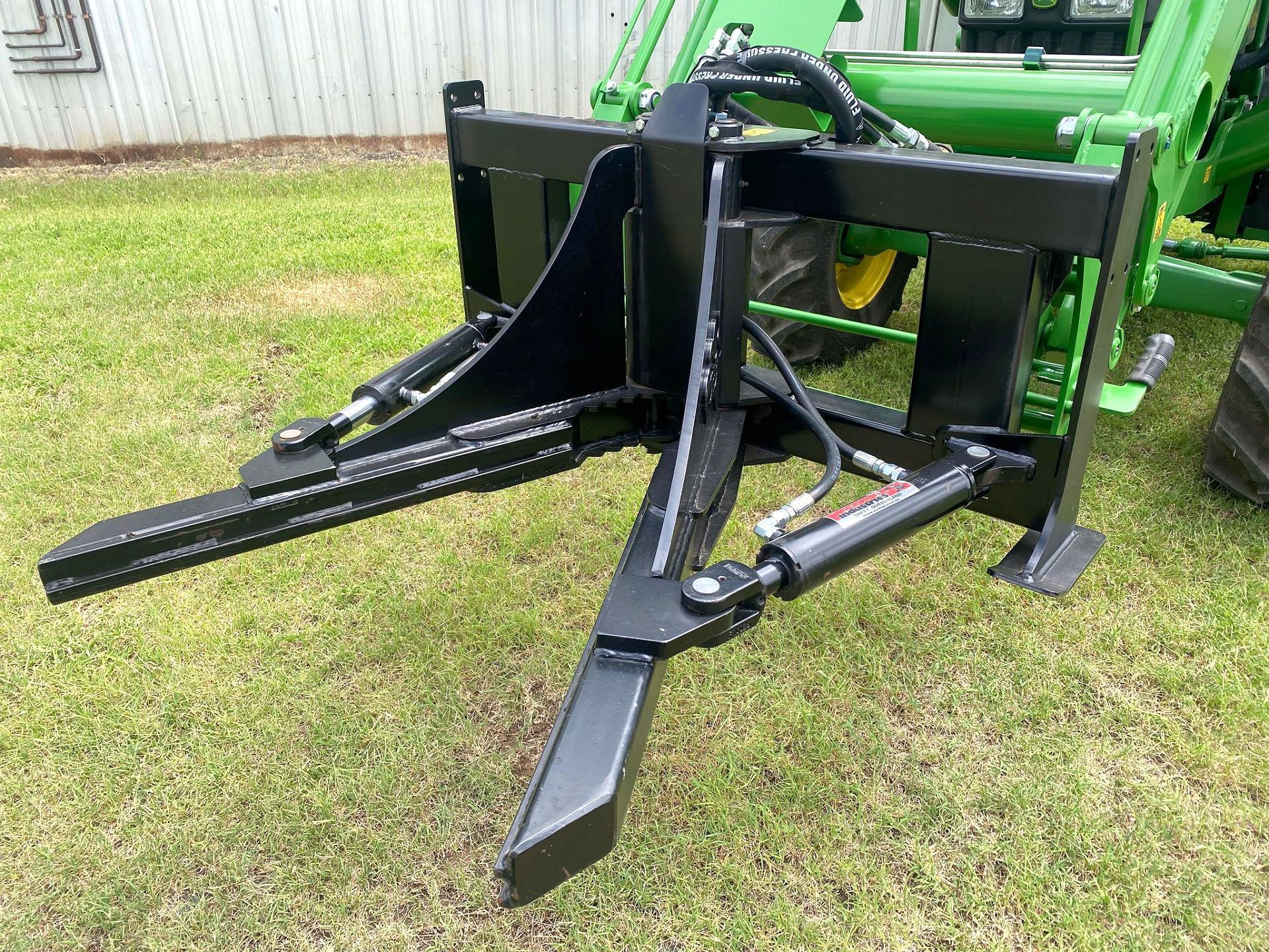 A McCormack Industries Brush Puller Front End Loader Attachment fitted to a John Deere Tractor