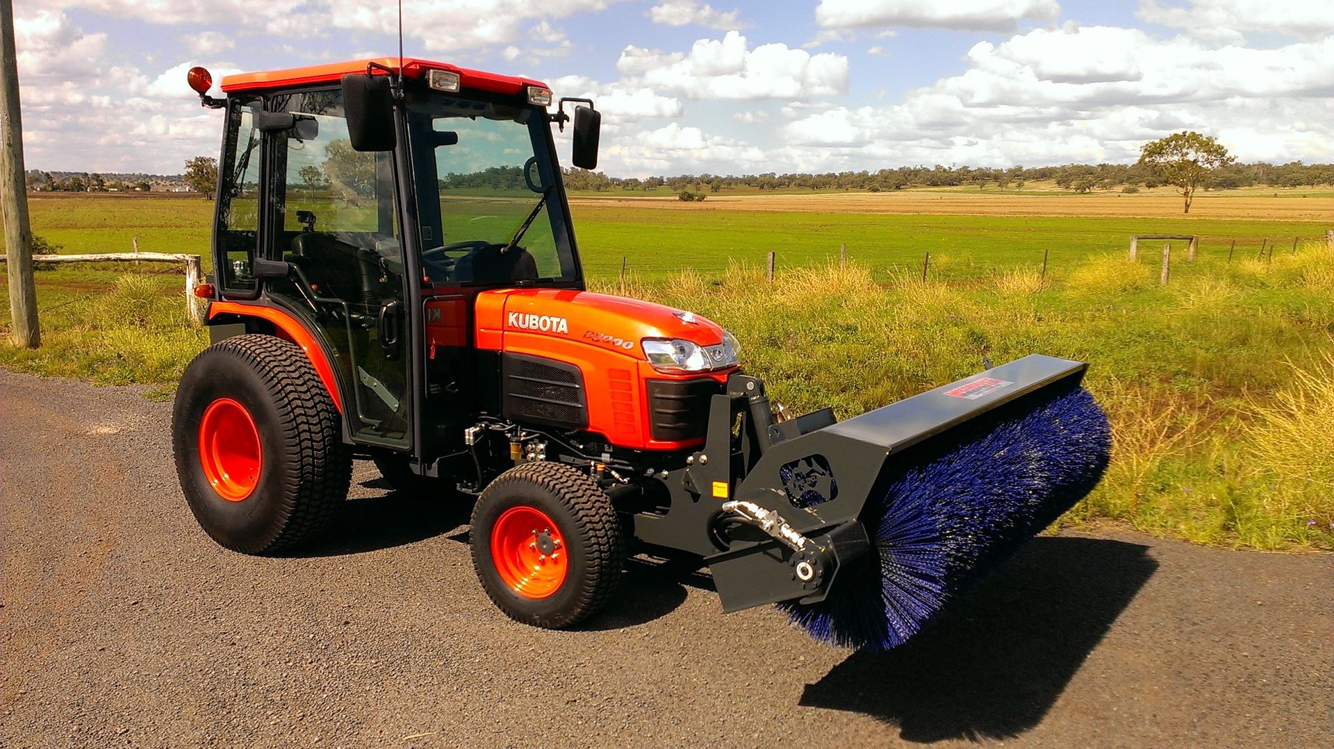 A photo of a McCormack front mounted road sweeper broom attchment fitted to a Kubota tractor