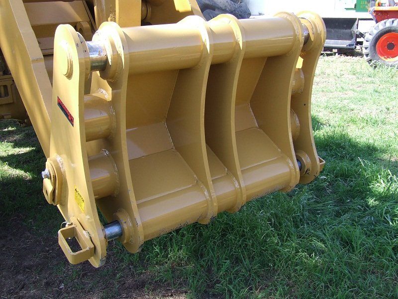 A close up of a bucket on a tractor in the grass