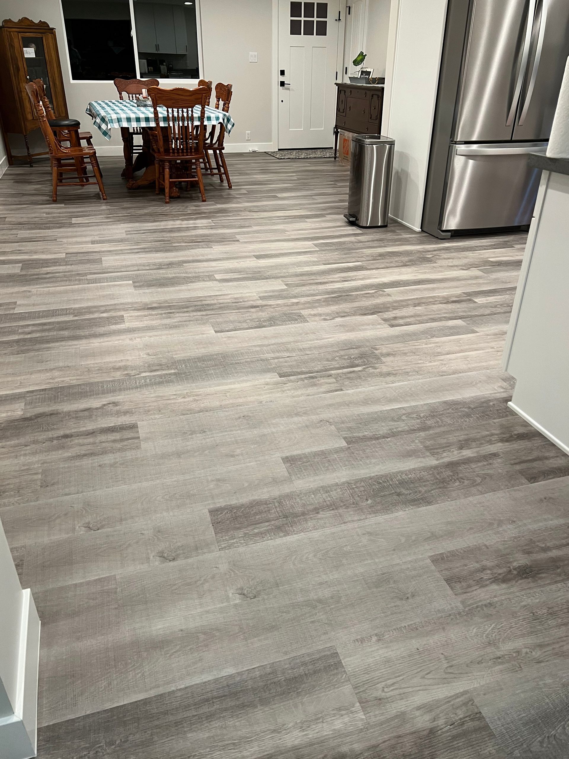 A kitchen with a dining table and chairs and a stainless steel refrigerator.