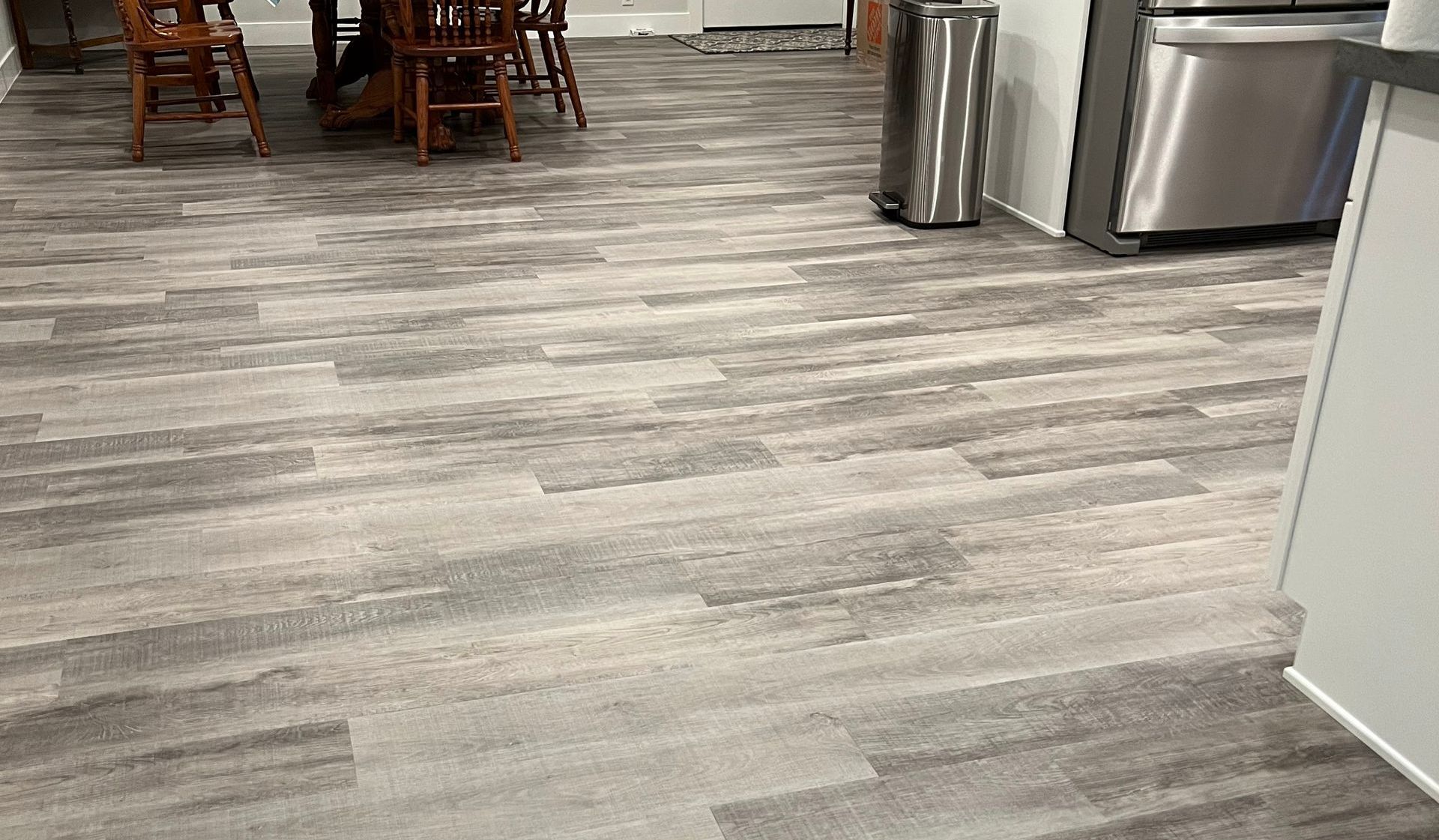 A kitchen with a wooden floor and a stainless steel refrigerator.