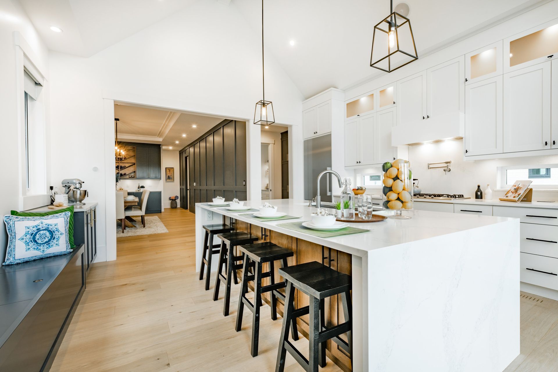 A kitchen with white cabinets and a large island with stools.