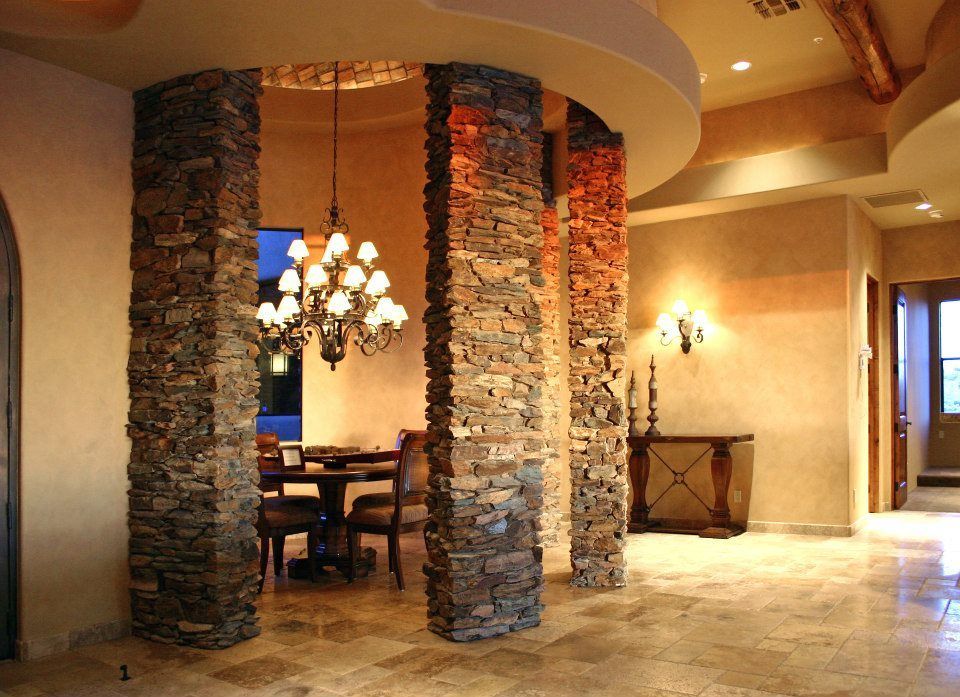 A dining room with stone pillars and a chandelier
