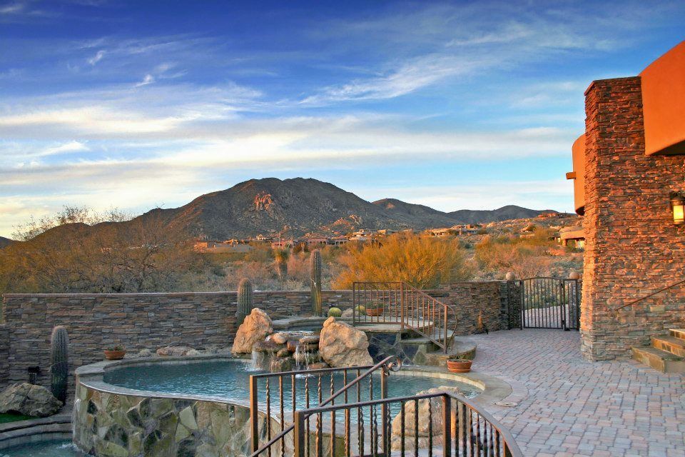 There is a large pool in the backyard of a house with mountains in the background.
