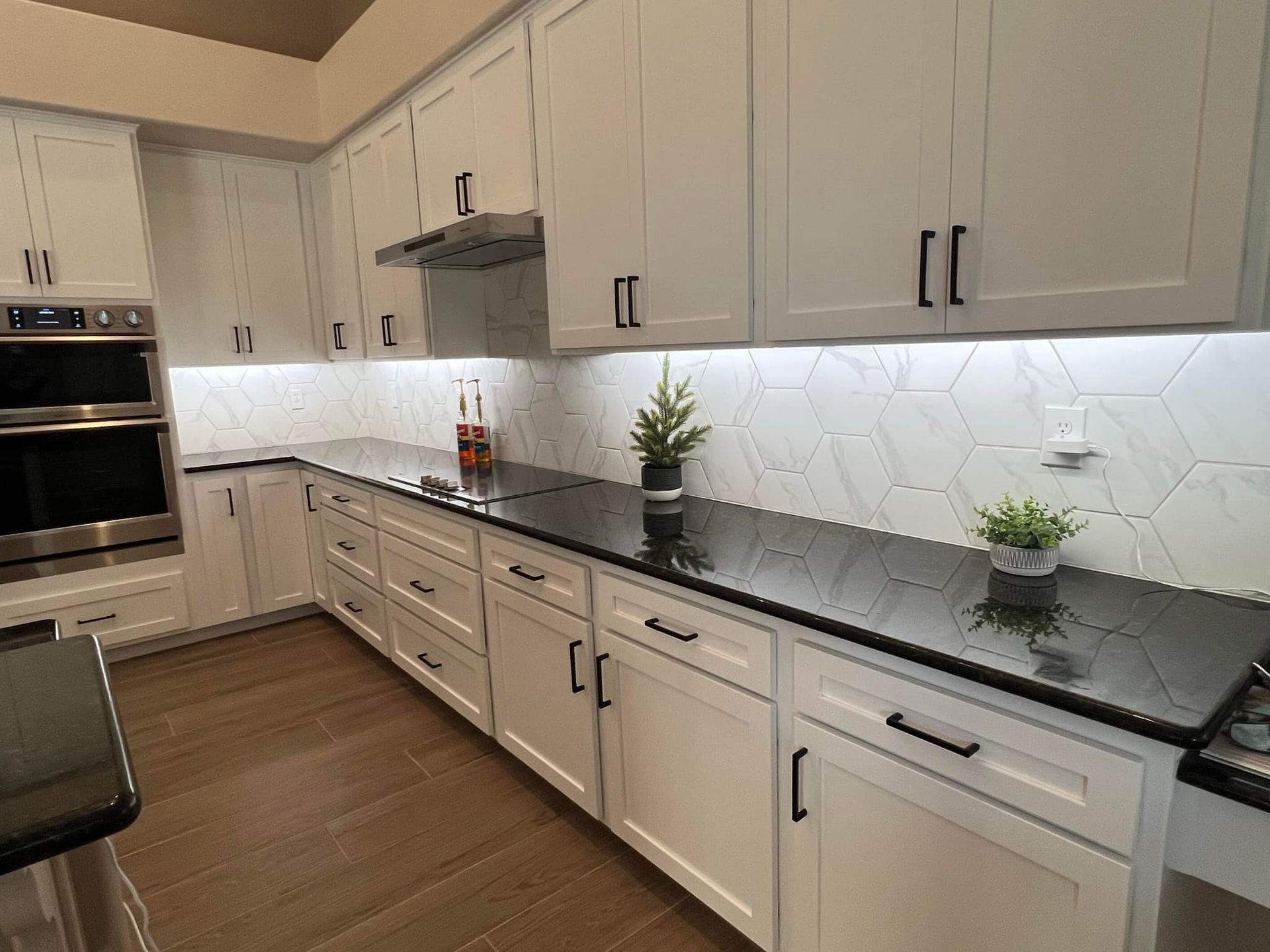 A kitchen with white cabinets and black counter tops.