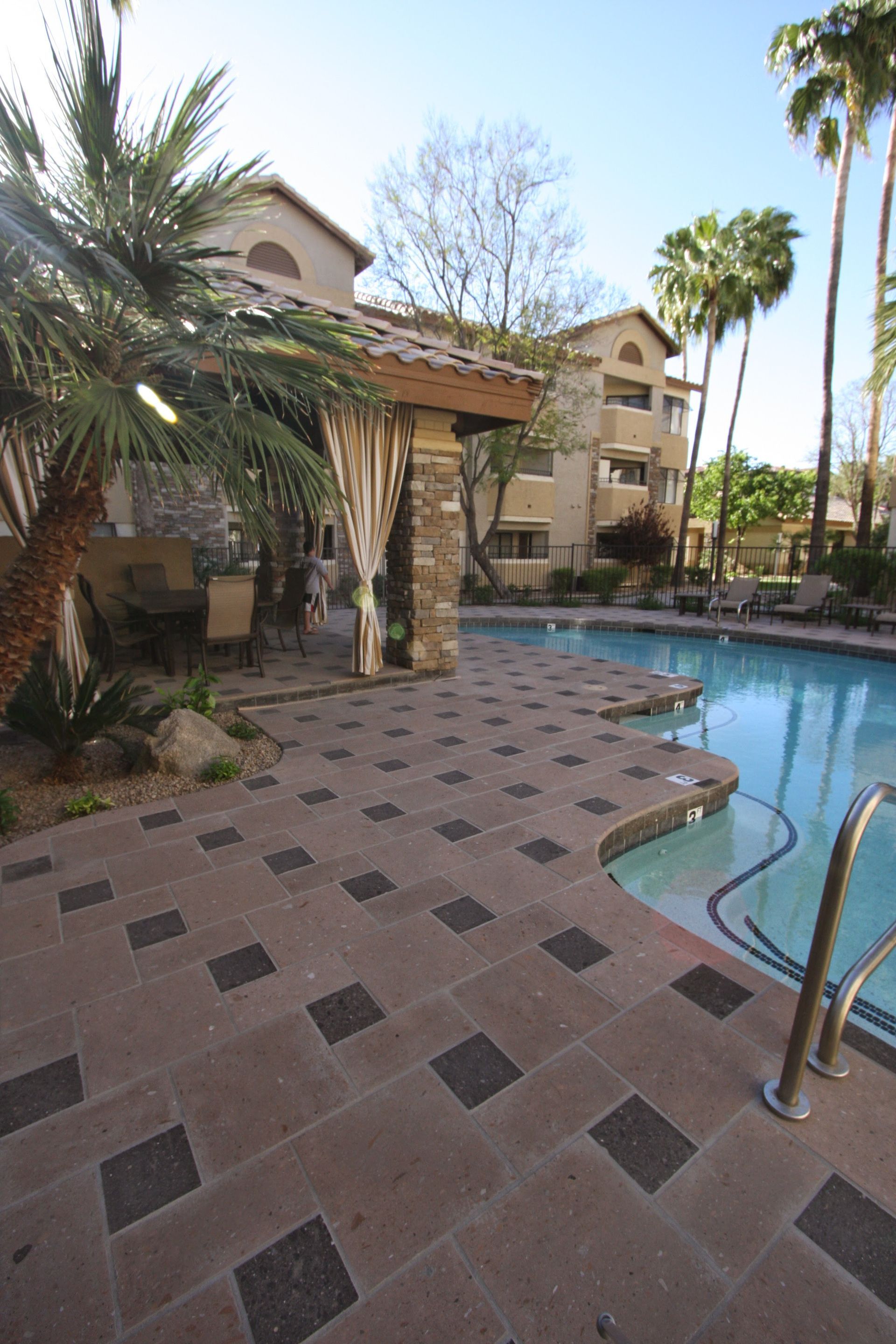 A large swimming pool in front of a building with palm trees
