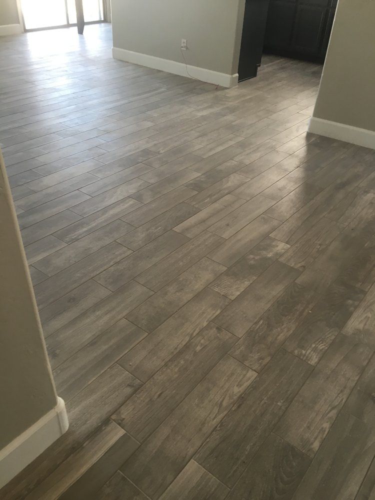 A living room with a wooden floor and a kitchen in the background.