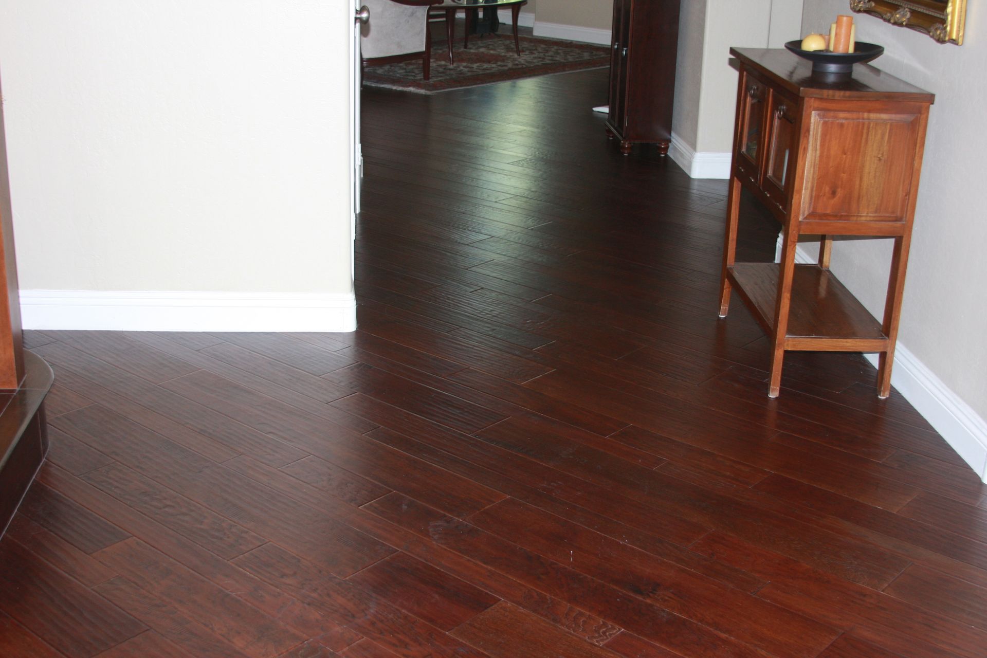 A wooden table with a bowl of fruit on it in a hallway