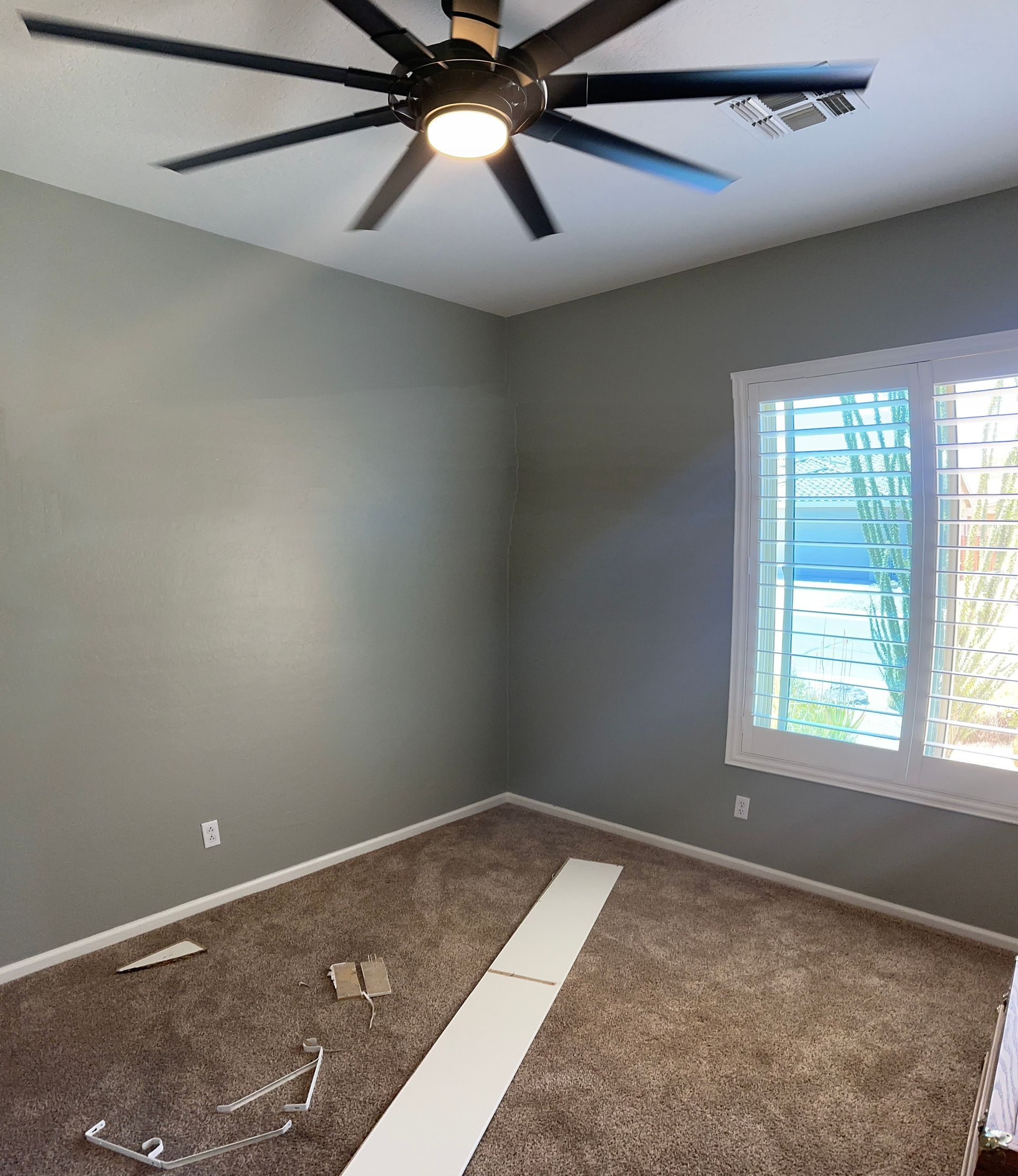 A bedroom with a ceiling fan and a window.