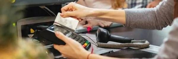 A woman is using a credit card machine to pay for a purchase.