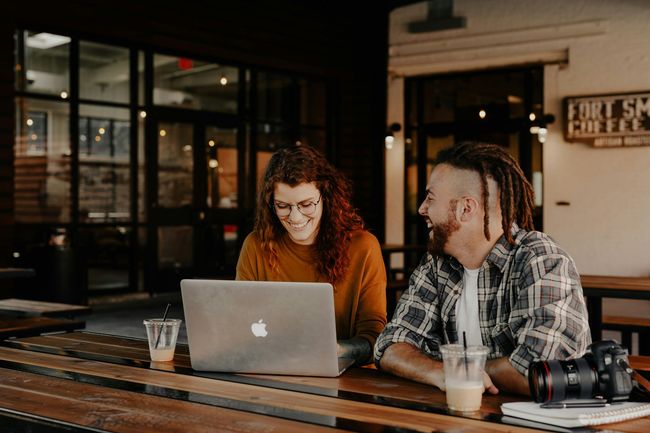 A man and a woman are sitting at a table with a laptop.