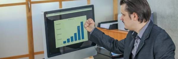 A man is pointing at a graph on a computer screen.